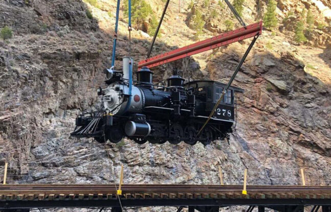 Winslow Crane Service is lifting a train car at the Cimarron Canyon Rail in Colorado