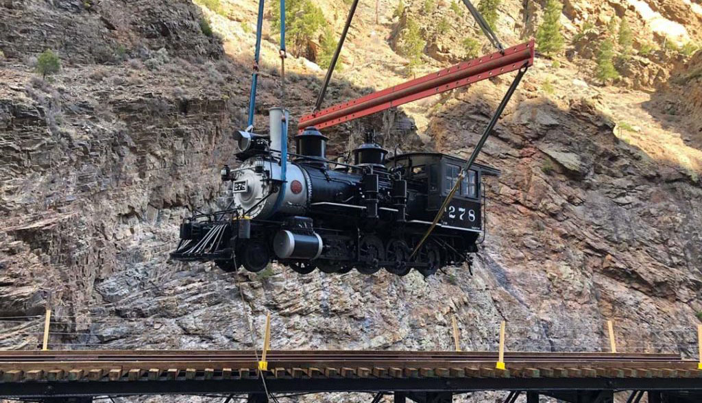 Winslow Crane Service is lifting a train car at the Cimarron Canyon Rail in Colorado