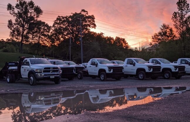 A fleet of white trucks lined up and parked on gravel road at Cherokee Truck Equipment in Chattanooga, Tennessee