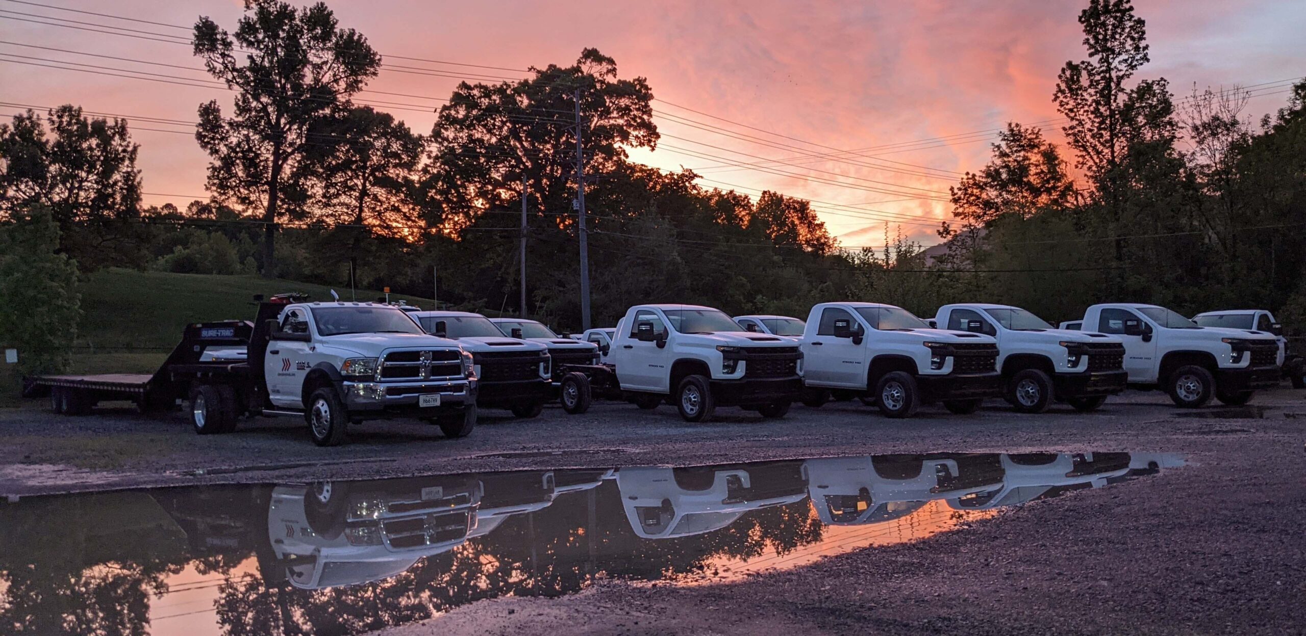 A fleet of white trucks lined up and parked on gravel road at Cherokee Truck Equipment in Chattanooga, Tennessee